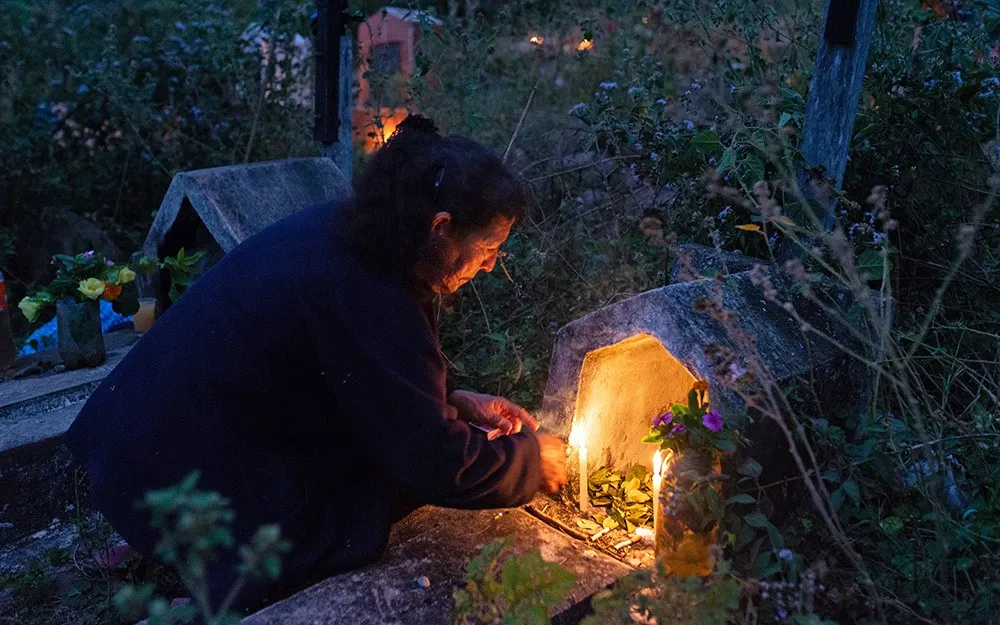 Julia lights candles for her parents who died from Chagas disease。