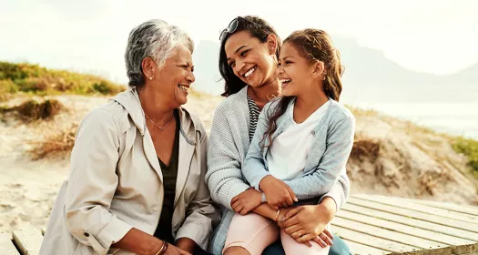 Grandmother，mother and daughter smiling and laughing on a beach