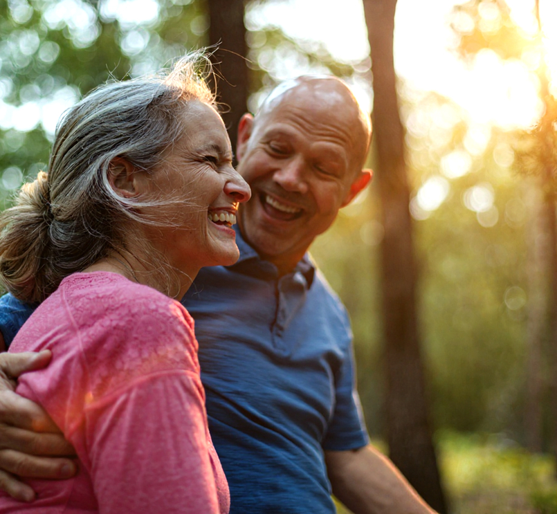 Elderly couple hugging in sunlit forest