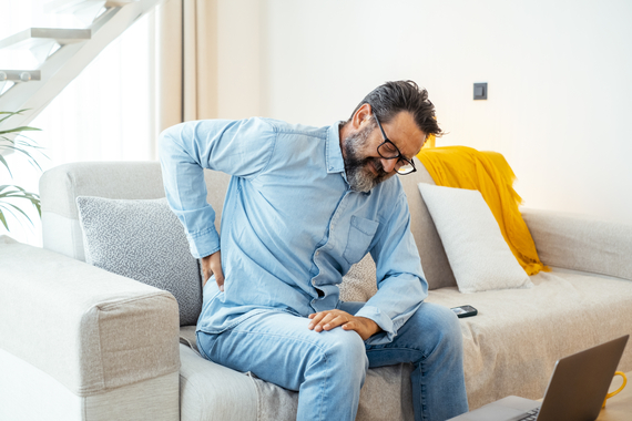 Imagen ilustrativa hombre sentado en el sofá con dolor de espalda