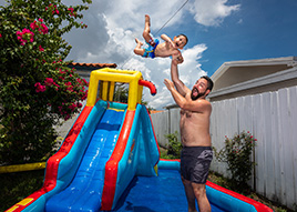 Vater und Sohn spielen mit einer Wasserrutsche im Garten