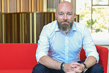 Mann sitzend auf dem Sofa und schaut direkt in die Kamera