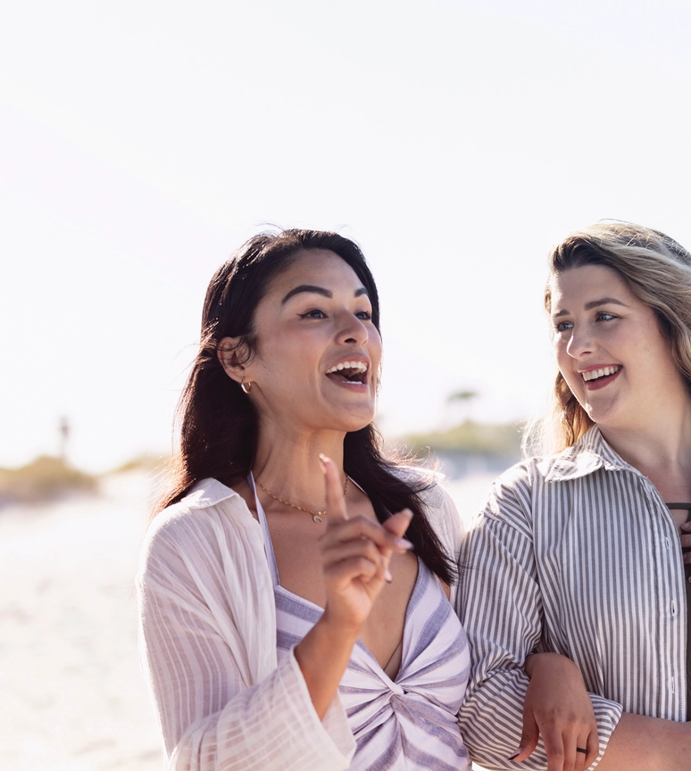 Two friends walking on the beach arm in arm
