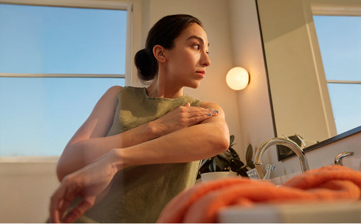 Mirror reflection of a patient in bathroom with towel and window view