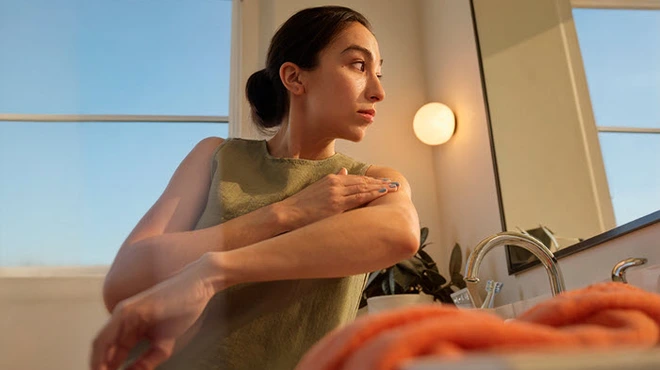 Mirror reflection of a patient in bathroom with towel and window view