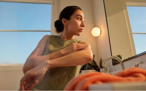 Mirror reflection of a patient in bathroom with towel and window view