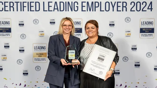 Two smiling persons with the award of Leading Employer 2024