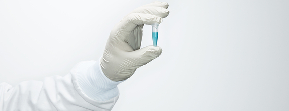 Gloved hand holding vial