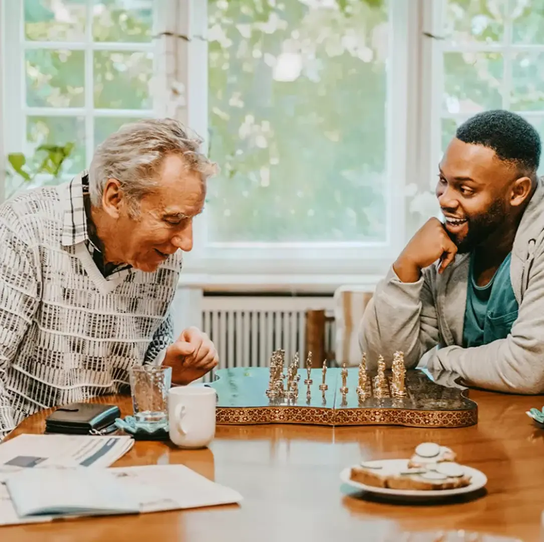 Young and senior man laughing while playing chess