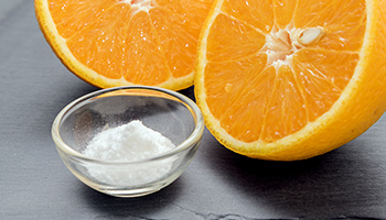 Eine geschnittene Orange und eine Tasse mit Vitamin-C-Pulver