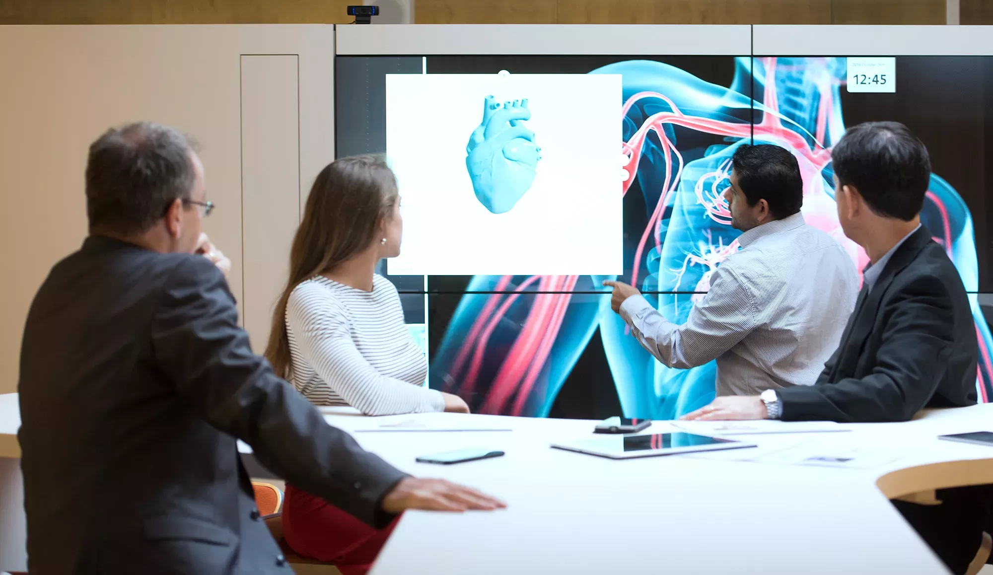 Mitarbeitende betrachten während eines Meetings die dreidimensionale Projektion eines Herzens / Des collaborateurs regardent la projection tridimensionnelle d'un cœur pendant une réunion