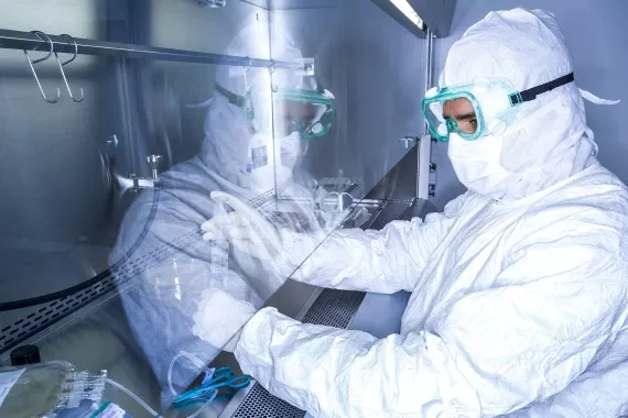Ein Wissenschaftler in Schutzkleidung arbeitet in einem Reinraum /  Un scientifique en tenue de protection travaille dans une salle blanche