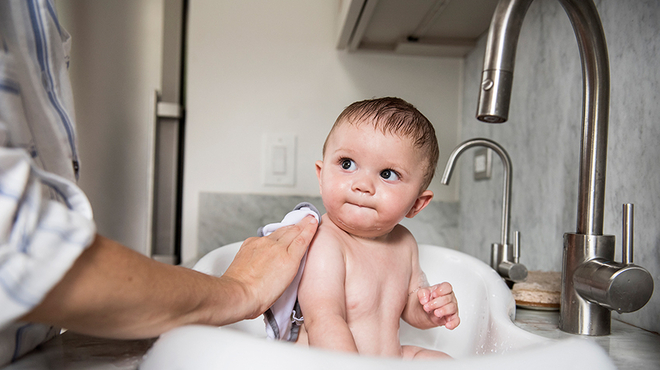 Die erste Zeit ist besonders wichtig für die Eltern-Kind-Bindung Vater badet Baby in der Badewanne