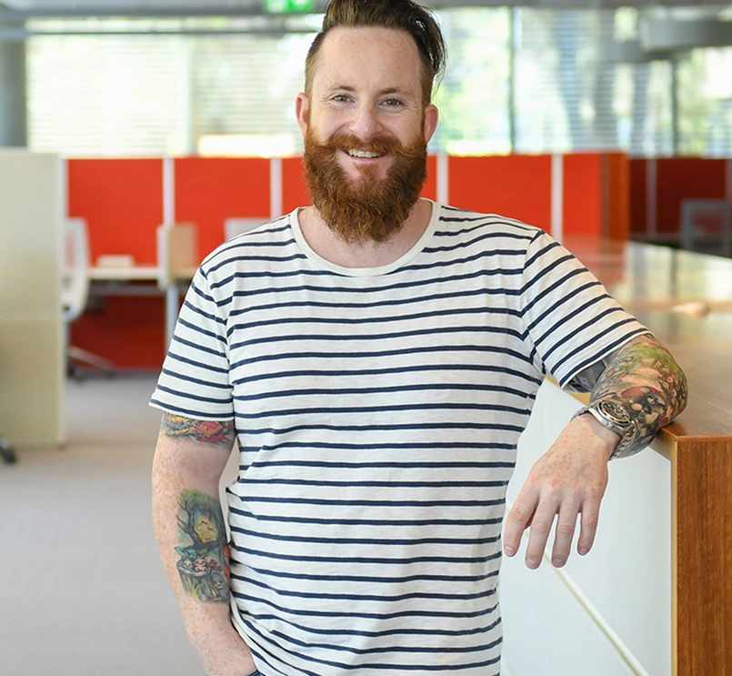 Un employé pose pour un portrait au milieu d'un espace de travail lumineux