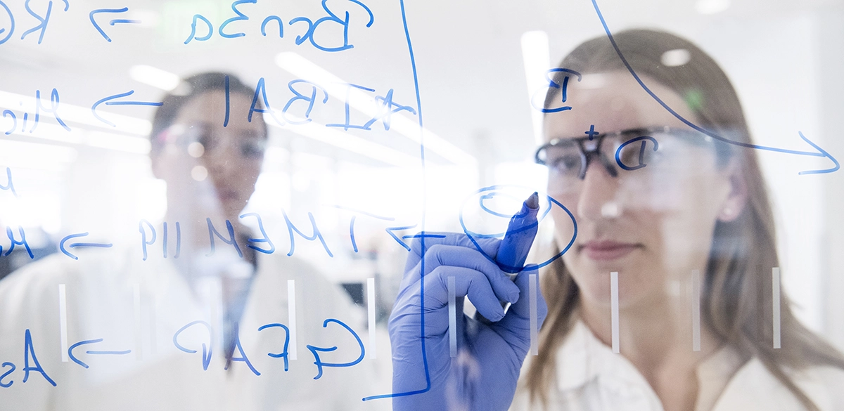 Scientifique écrivant sur une surface vitrée