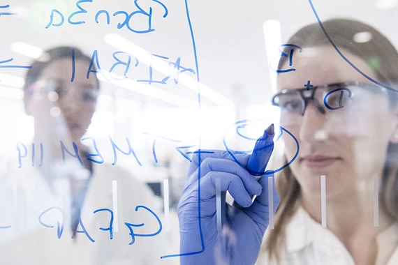 Scientifique écrivant sur une surface vitrée