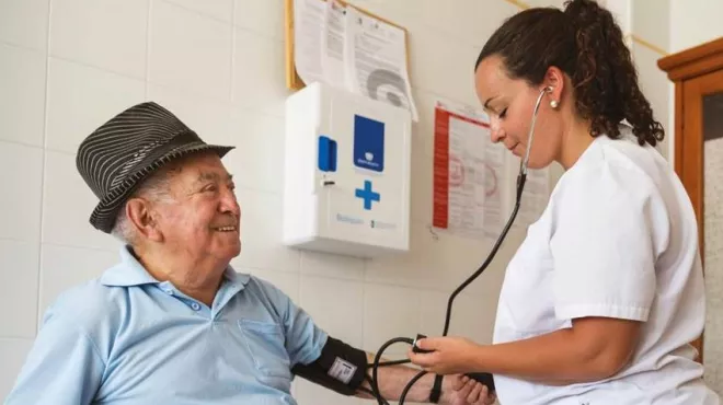 Eine Ärztin misst den Blutdruck eines älteren Patienten / Prise de tension artérielle d'un patient agé