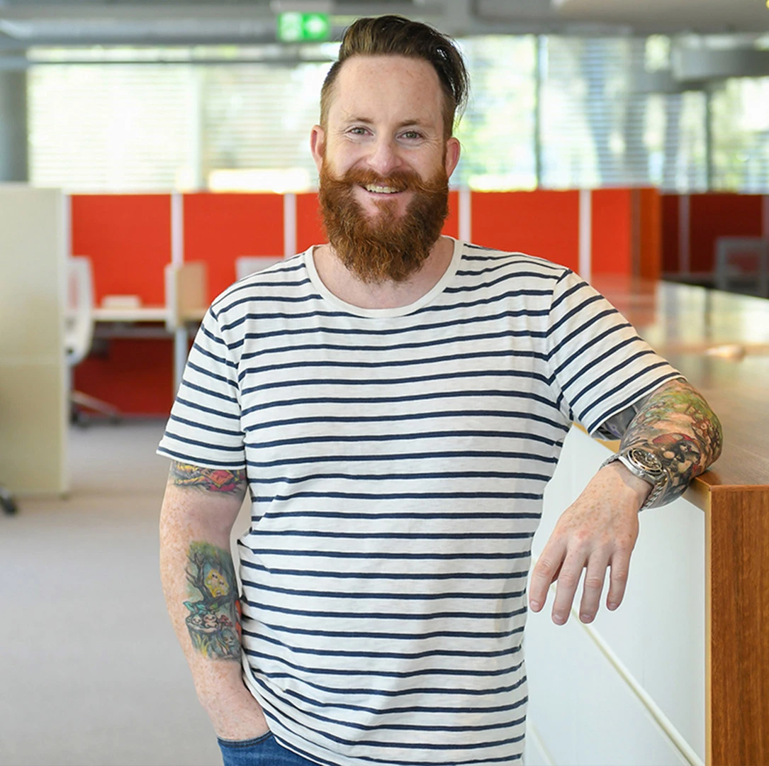 Un employé pose pour un portrait au milieu d'un espace de travail lumineux