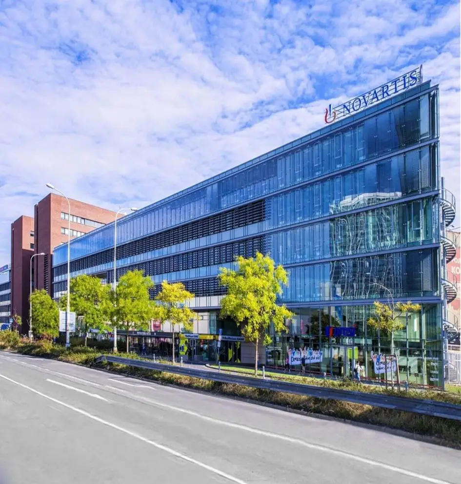 Modern glass office building of Novartis headquarters in Prague under a blue sky