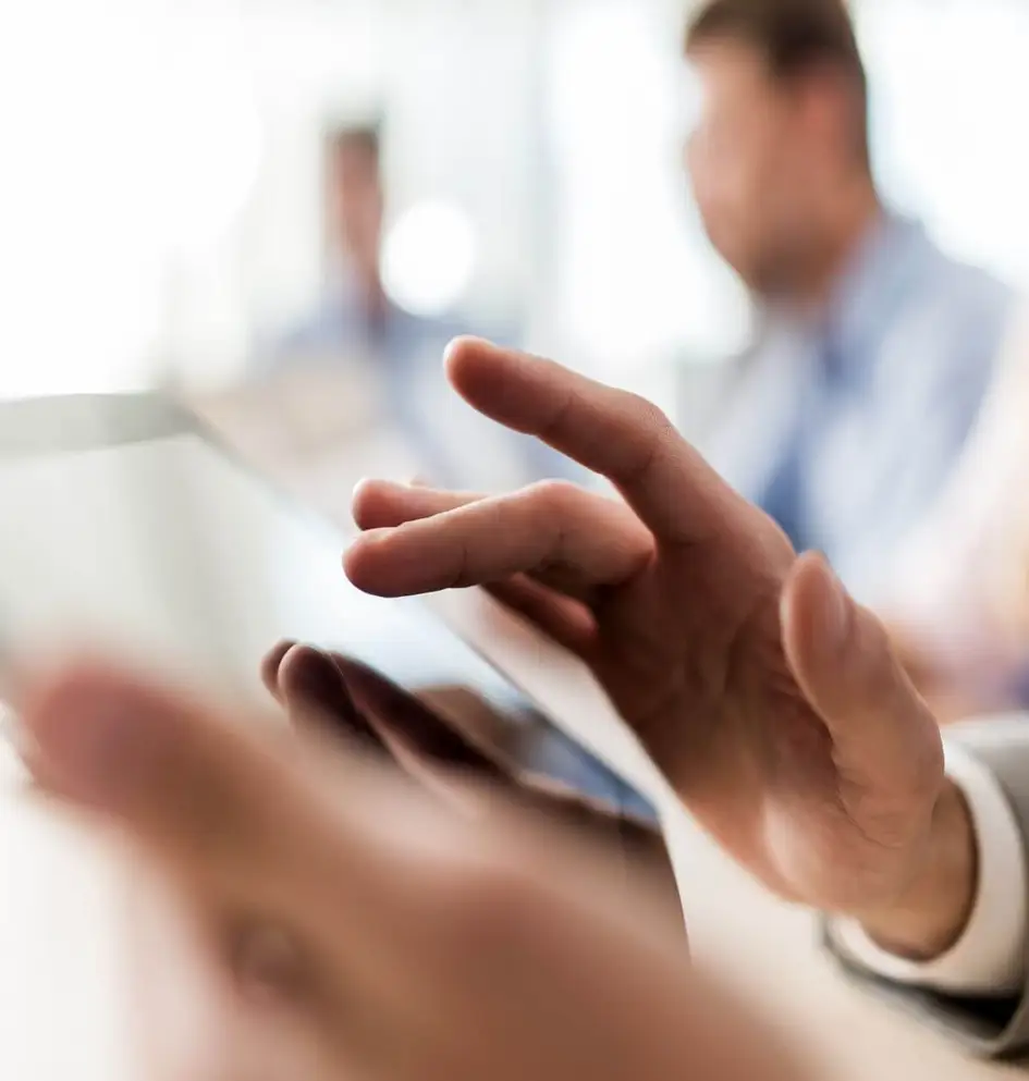 Close-up of a person's hand interacting with a digital tablet screen in a professional setting