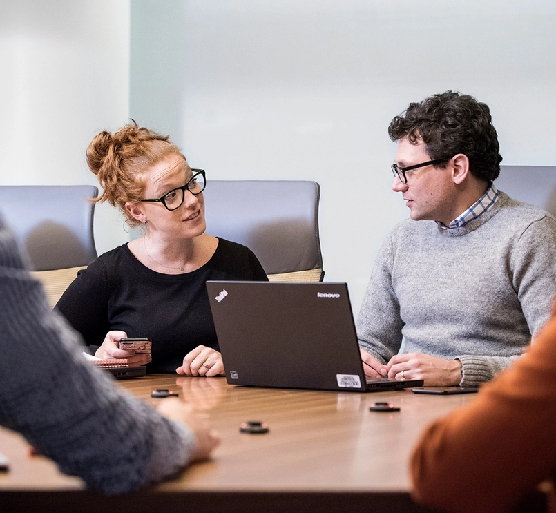 Group of people in a meeting discussing over a computer