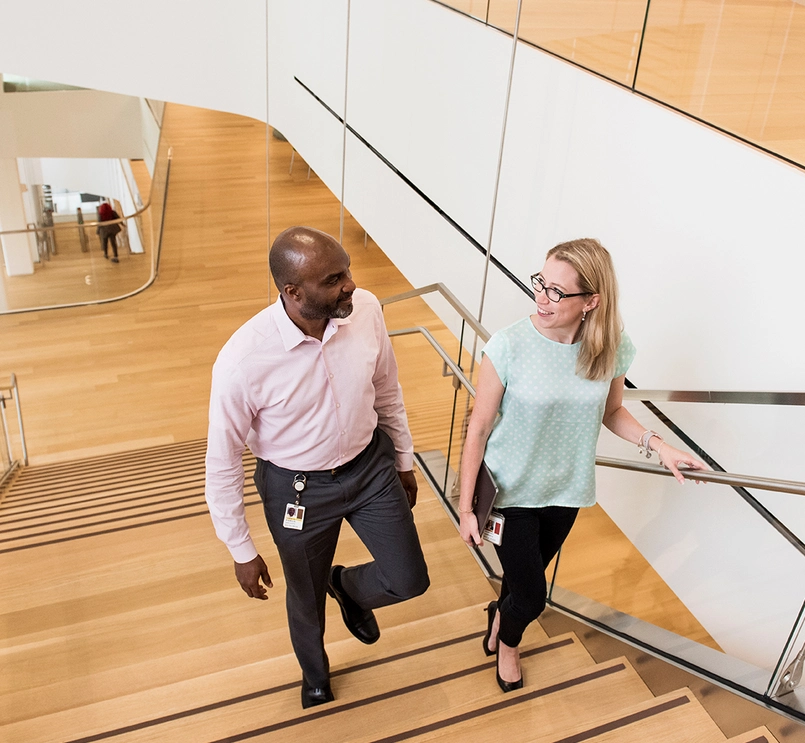 Two people walking up stairs and talking to each other