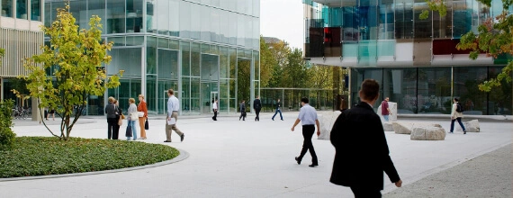 Courtyard of a modern Novartis corporate campus with glass buildings and walking pedestrians