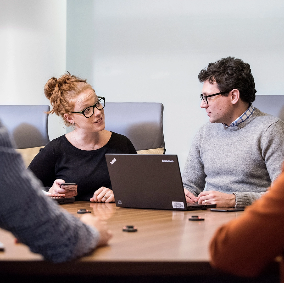 Group of people in a meeting discussing over a computer