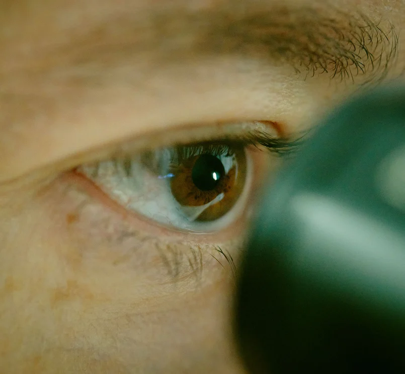 Nahaufnahme einer Person, die in ein Mikroskop blickt.