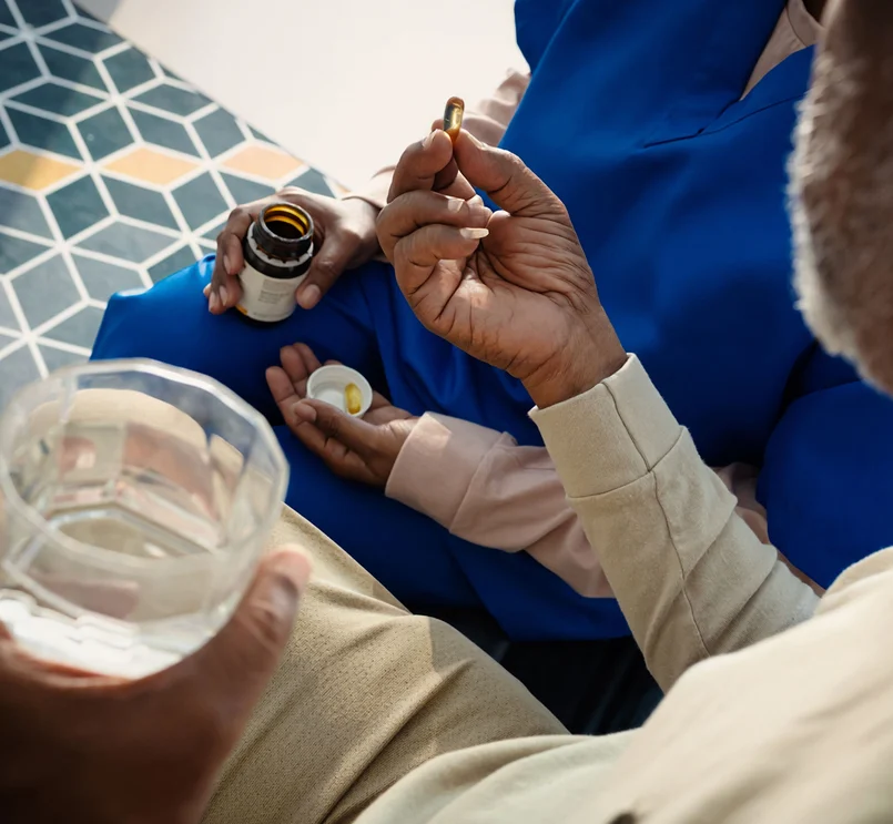Medizinische Fachkraft verabreicht einem Patienten ein Medikament zum Einnehmen.