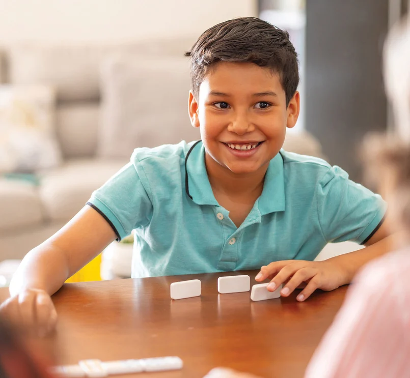 Kinder spielen Domino am Tisch.