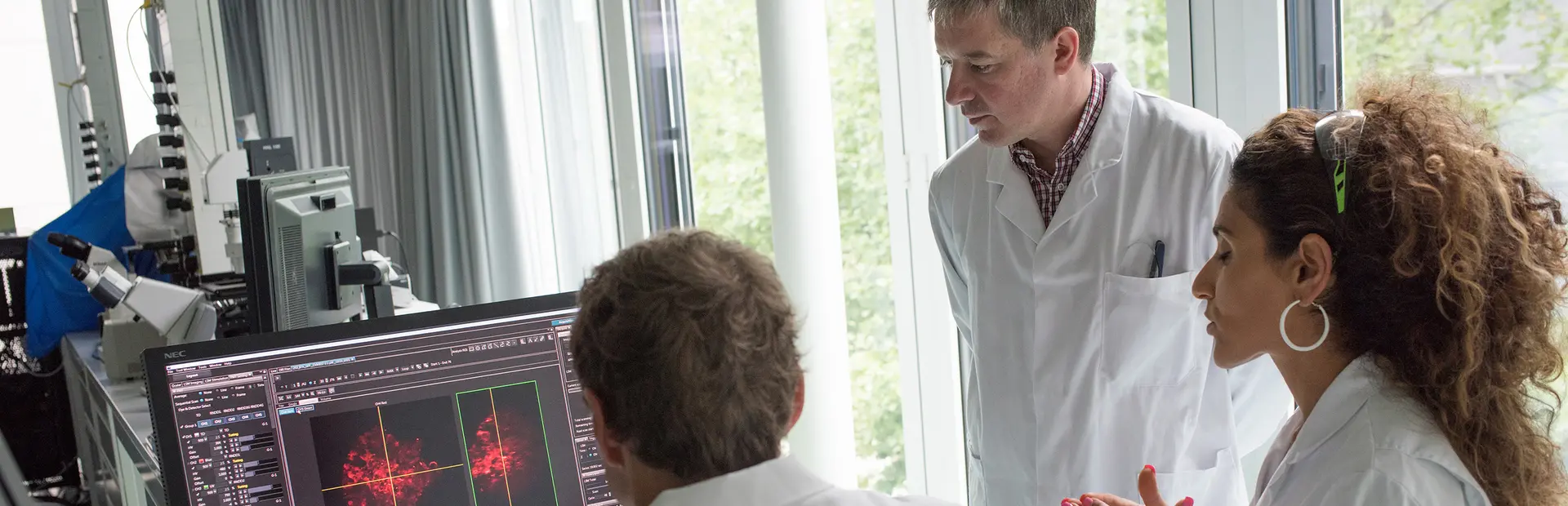 3 Wissenschaftler*Innen diskutieren vor Bildschirm