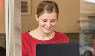 Junge Frau sitzt in einem Cafe vor dem Laptop