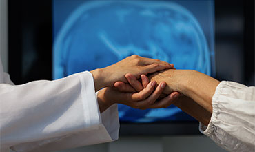 Mehrere Hände halten die Hand einer Person vor einem blau leuchtenden Hintergrund
