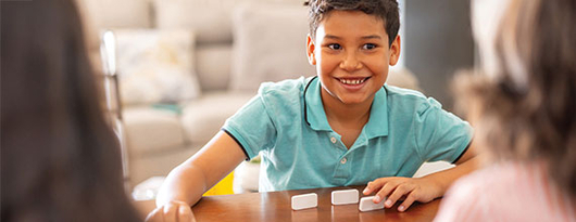 Kinder spielen Domino am Tisch.