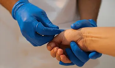 Ärzte untersuchen die Hand eines Patienten vor einem Gehirnscan