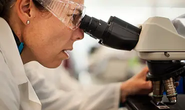 Wissenschaftlerin arbeitet mit einem Mikroskop im Labor.