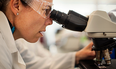 Wissenschaftlerin arbeitet mit einem Mikroskop im Labor.