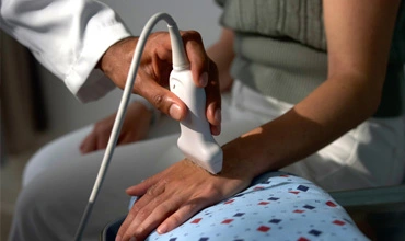 Medizinischer Eingriff mit einem Ultraschallgerät an der Hand eines Patienten in einer klinischen Umgebung