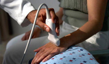 Medizinischer Eingriff mit einem Ultraschallgerät an der Hand eines Patienten in einer klinischen Umgebung