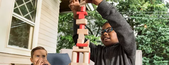 zwei Kinder bauen mit Holzklötzen einen Turm