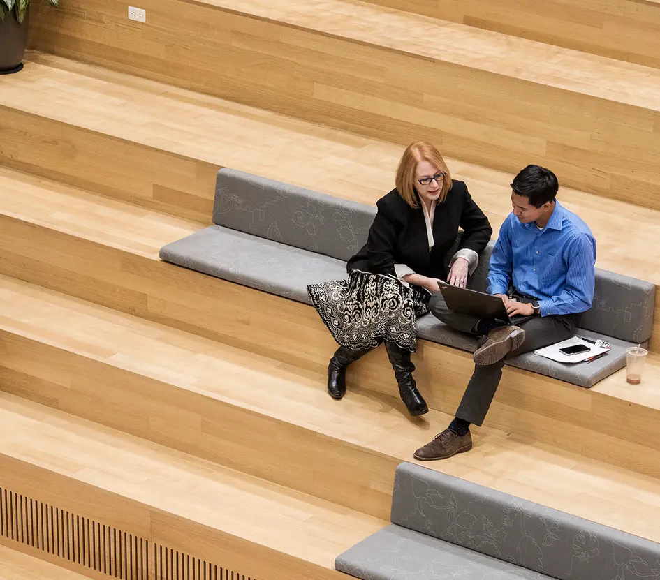 Kolleg*innen sitzen auf der Treppe am Laptop