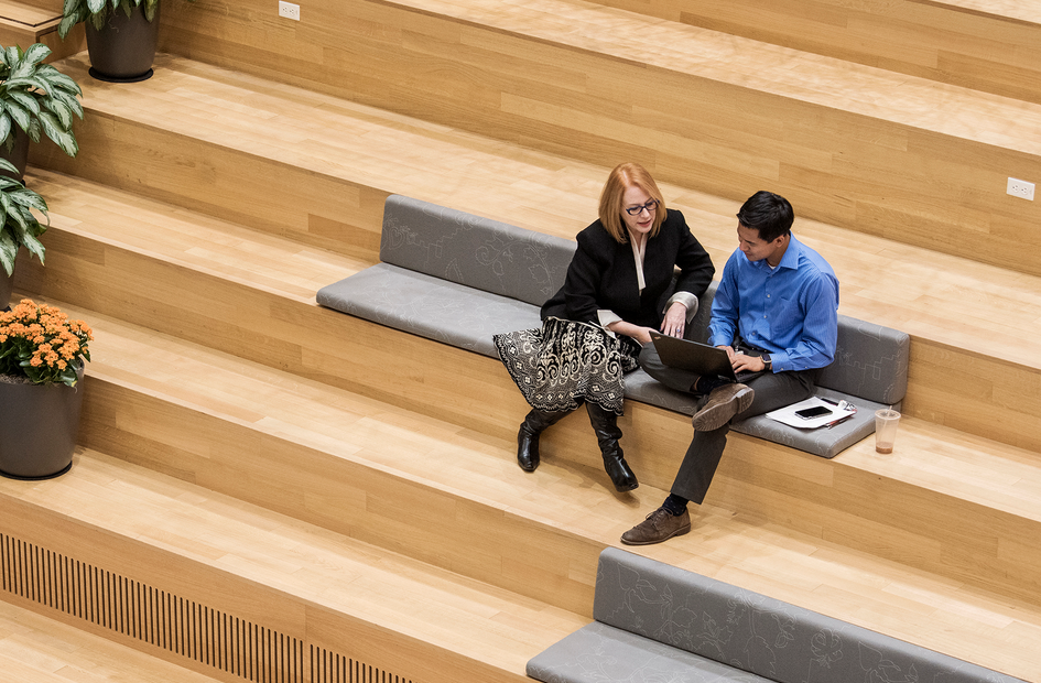 Kolleg*innen sitzen auf der Treppe am Laptop