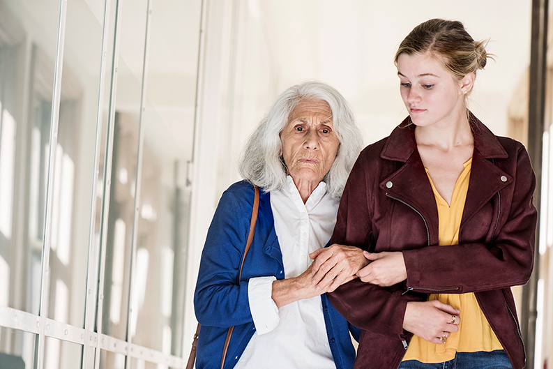 Ältere Dame wird von junger Frau gestützt