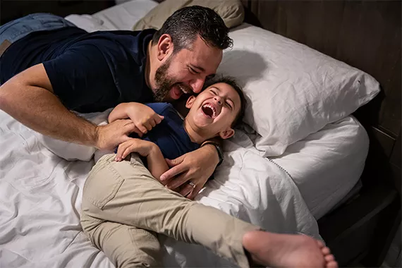 Ein Vater tobt mit seinem Sohn im Bett