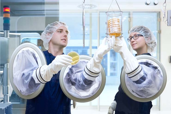 Zwei Wissenschaftler stehen in der Produktion und schauen sich einen Behälter an