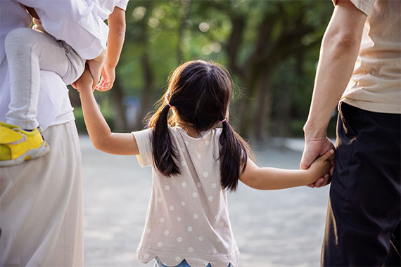 Familie hält Hand in Hand im Park.