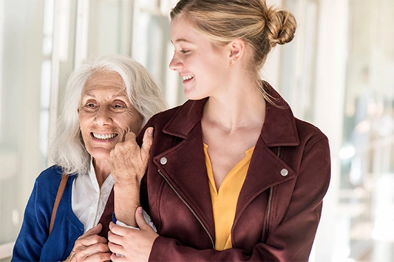Eine ältere Frau hält sich am Arm einer jüngeren fest.