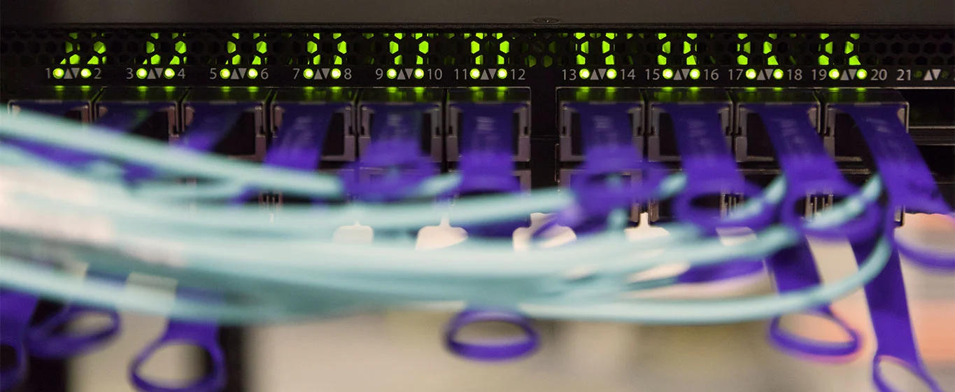 Glasfaserkabel, die mit einem Netzwerkswitch verbunden sind, mit LED-Anzeigen.