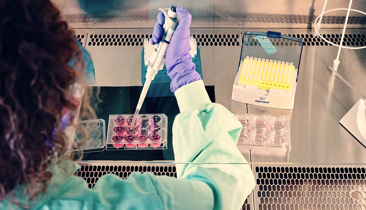 Wissenschaftlerin im Labor bereitet Proben mit Pipette und Reagenzglaesern vor.